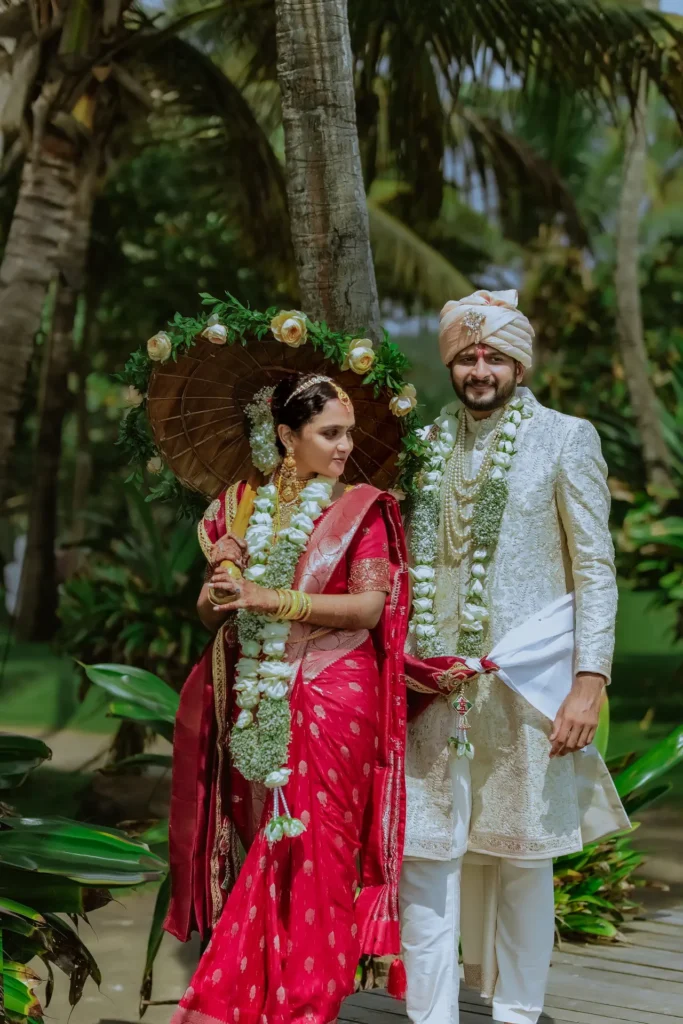 Bride and groom in traditional attire by the palm trees at Taj Green Cove